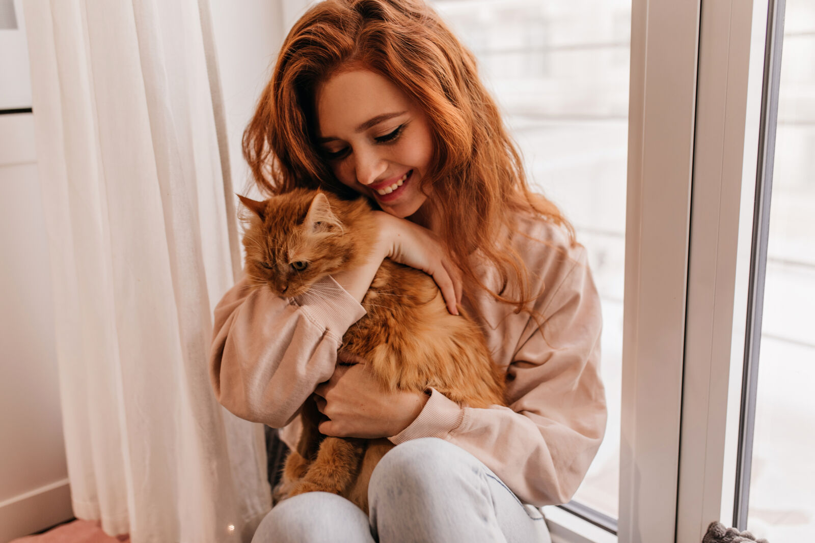 A girl hugging a ginger cat.