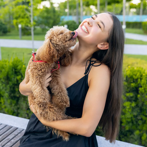 A woman hugging a small, brown dog